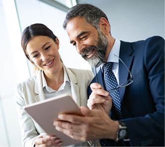 Happy business colleagues in modern office talking and using tablet